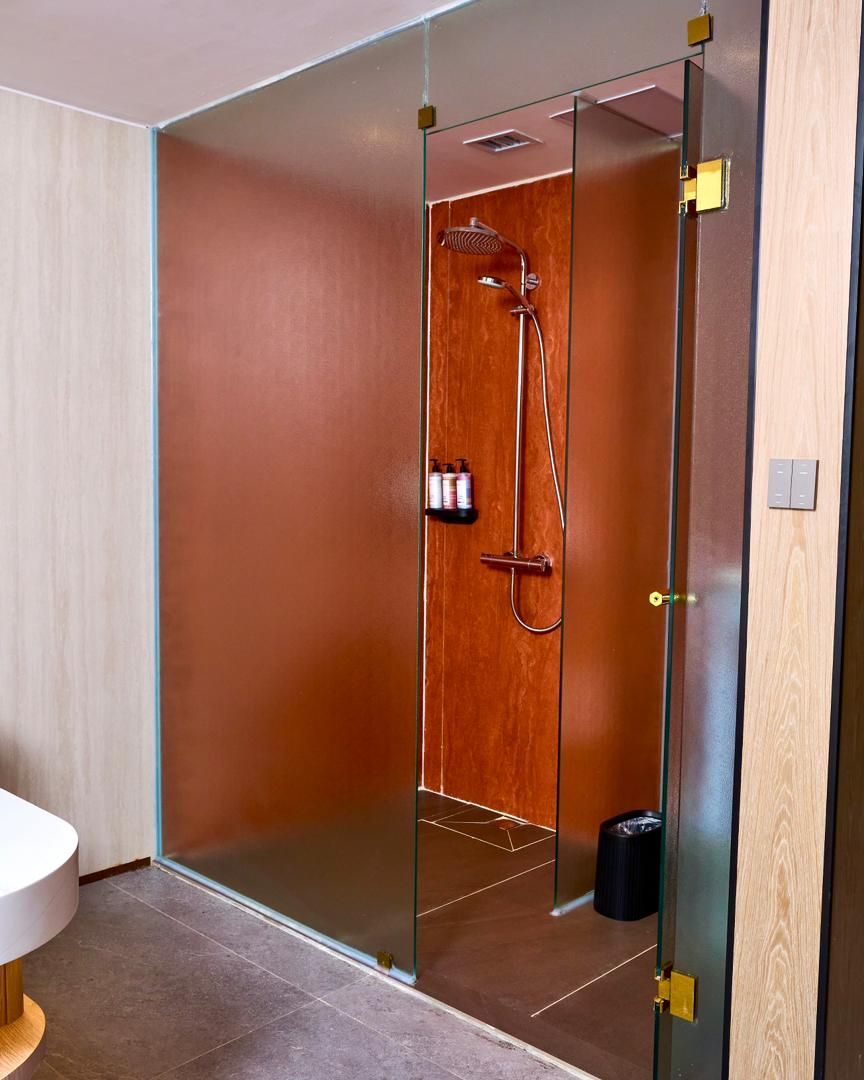 Un baño moderno con mampara de vidrio, ducha y retrete.