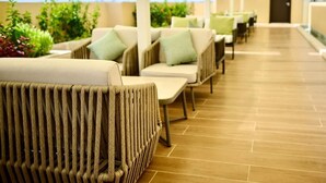 A covered outdoor seating area with wicker furniture and a tiled floor.