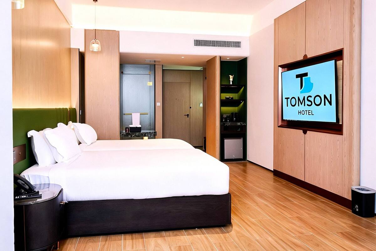 Una habitación de hotel moderna con una cama grande, un televisor y piso de madera.