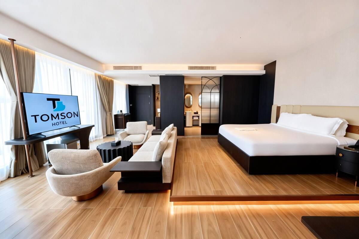 Una habitación de hotel moderna con una cama grande, un sofá, un televisor y un escritorio.