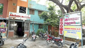 A building with a sign for 'Akshaya Mahalakshmi' and another sign advertising rooms for rent. - Akshaya Mahal A/C Rooms (Anapirandan)