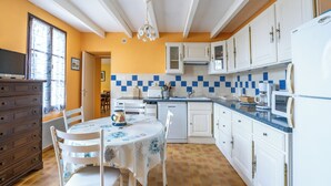 A kitchen with white cabinets, a blue countertop, and a dining table with chairs. - Cure or vacation a quiet house with a view of the castle (Jonzac)