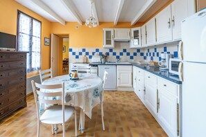 A kitchen with white cabinets, a blue countertop, and a dining table with chairs. - Cure or vacation a quiet house with a view of the castle (Jonzac)