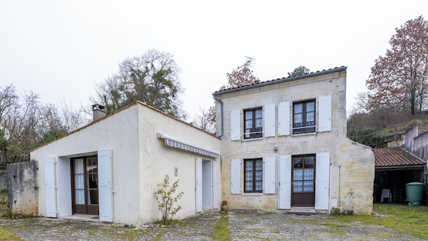 A two-story building with a stone facade, a small garden area, and a paved courtyard. - Cure or vacation a quiet house with a view of the castle (Jonzac)