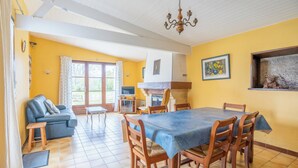 A dining area with a table set for four, wooden chairs, a blue tablecloth, and a chandelier. - Cure or vacation a quiet house with a view of the castle (Jonzac)