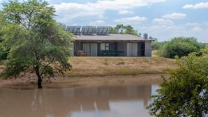 Uma casa moderna com telhado plano, painéis solares e vista para a água.