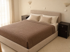 A bedroom with a bed, nightstands, and wall sconces. - Garden-View Apartment with Private Courtyard (Faliraki)