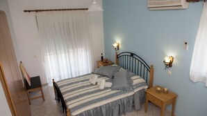 Een slaapkamer met een bed, nachtkastjes, een garderobe en een airconditioner.