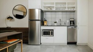 A compact kitchen with a refrigerator, microwave, coffee maker, and dishwasher. - The Artesian (Denver)