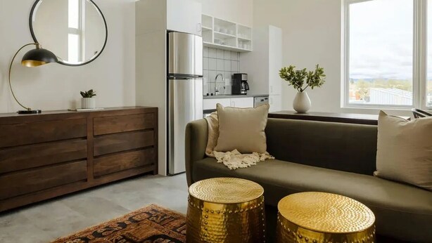 A modern kitchen with a refrigerator, coffee maker, and white cabinets. - The Artesian (Denver)