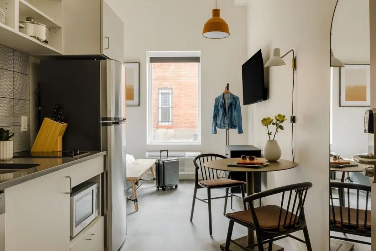 A compact kitchen with a modern refrigerator, a sink, and a dining area with chairs and a table.