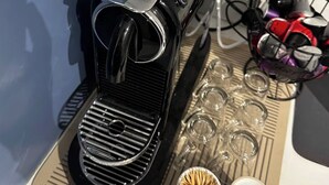 A black espresso machine on a countertop with a power outlet above it. - Luxury 3BR Escape - Pools and Gardens (Qala)