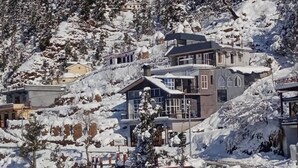 A multi-story building with a mix of architectural styles, surrounded by snow-covered trees and a mountainous backdrop. - The Celebrè- A Little Castle Homestay  (Tehri)