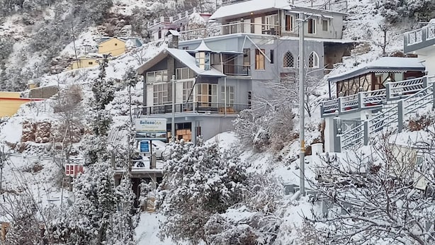 A multi-story building with balconies, a sign for 'Belleza Inn,' and a snow-covered landscape. - The Celebrè- A Little Castle Homestay  (Tehri)