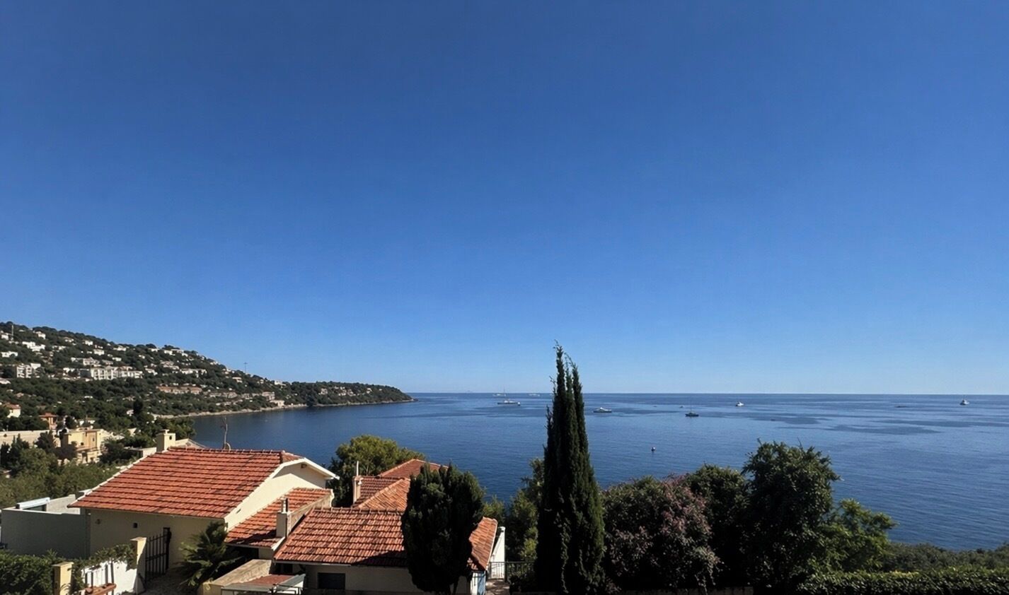 A coastal view with buildings, a clear sky, and calm sea.