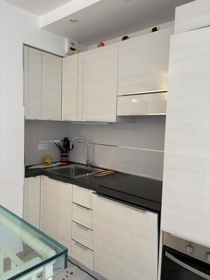 A modern kitchen with white cabinetry, a black countertop, and a stainless steel sink. - Monaco Grand Prix F1, Sea View, Pool, Private Box, Calm, sand beach, transport (Roquebrune-Cap-Martin)