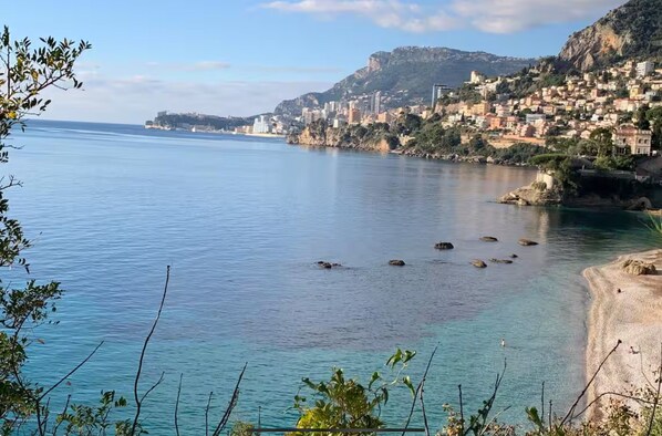 A coastal town with buildings along the shoreline, calm sea, and rocky outcrops. - Monaco Grand Prix F1, Sea View, Pool, Private Box, Calm, sand beach, transport (Roquebrune-Cap-Martin)