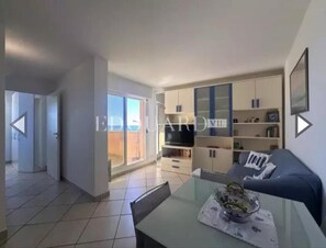 A modern living room with a sofa, a dining table with chairs, a TV, and a bookshelf. - Monaco Grand Prix F1, Sea View, Pool, Private Box, Calm, sand beach, transport (Roquebrune-Cap-Martin)