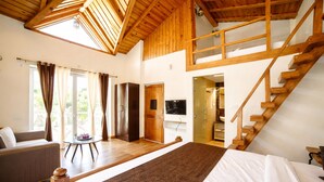 A bedroom with a large bed, a sofa, a wooden staircase, and a TV. - Four Farm - Best Resort In Nainital For Family (Nainital)