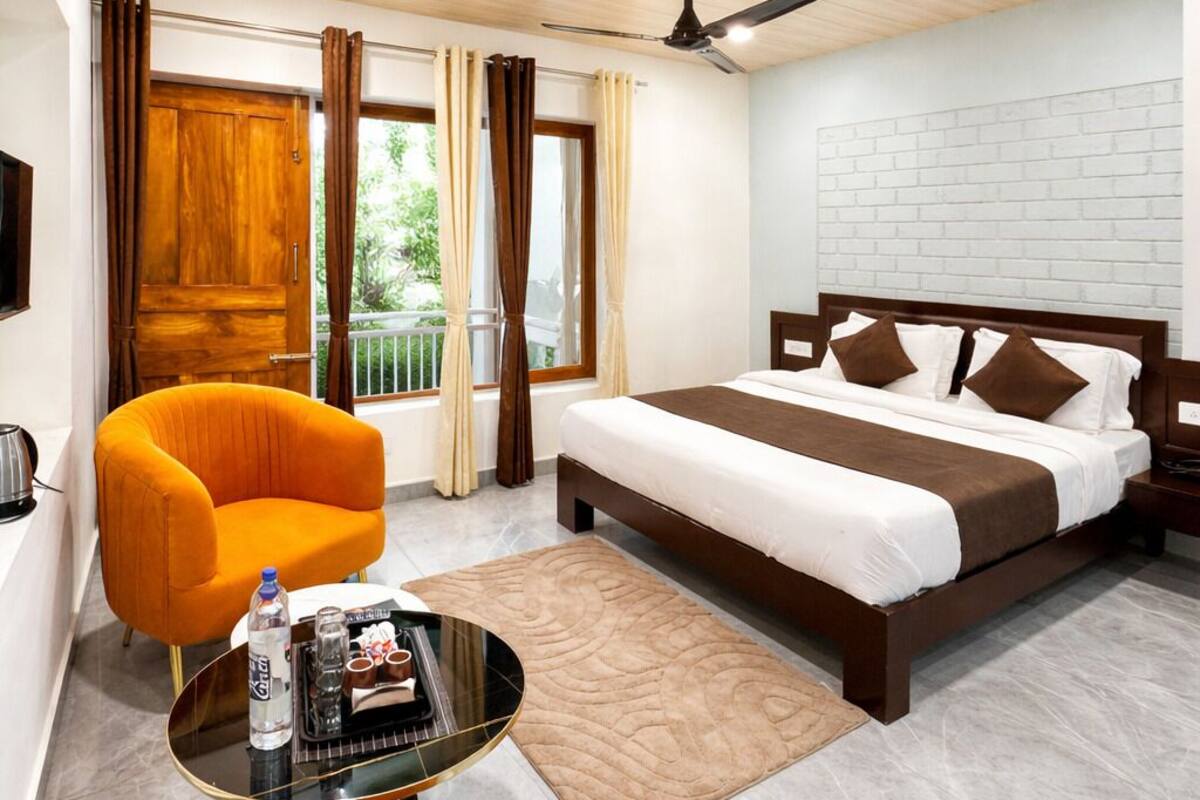 A hotel room with a bed, a chair, a table, and a ceiling fan.