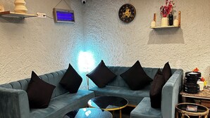 A modern living room with a blue sectional sofa, round coffee tables, and ottomans. - Four Farm - Best Resort In Nainital For Family (Nainital)