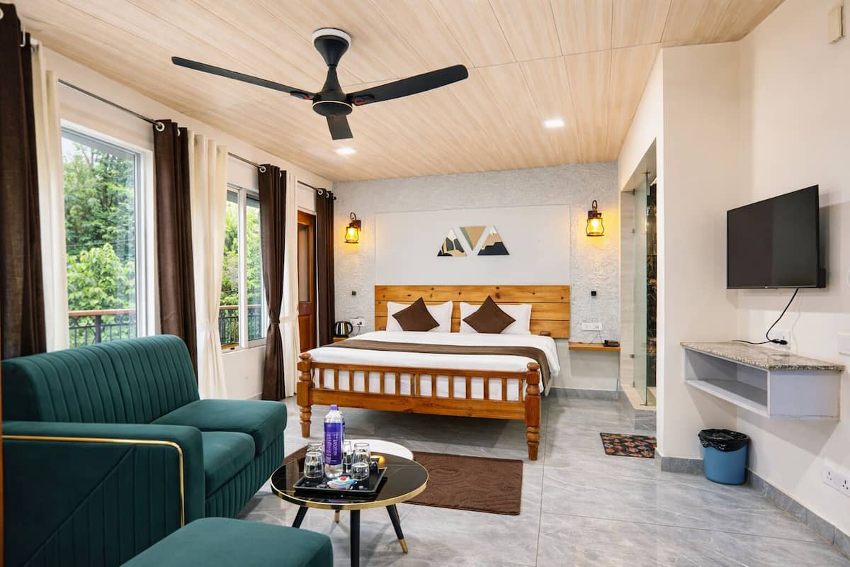 A hotel room with a bed, a sofa, a TV, a ceiling fan, and a window with curtains.