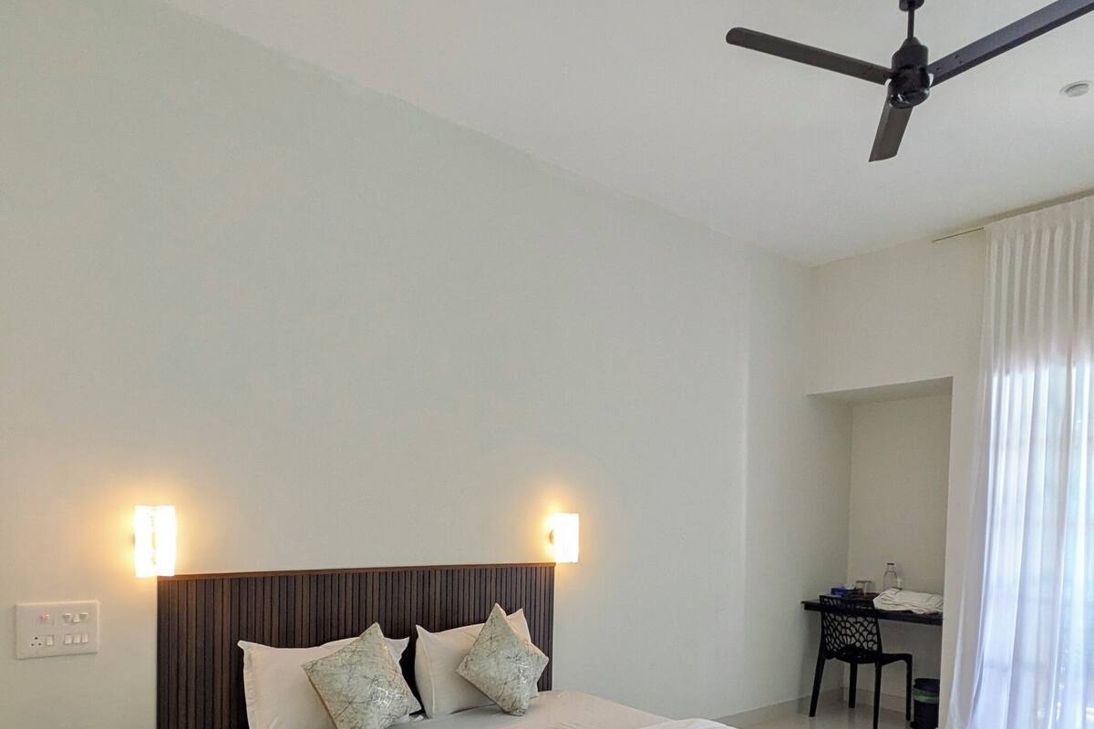 Una habitación de hotel moderna con una cama grande, un escritorio y un ventilador de techo.