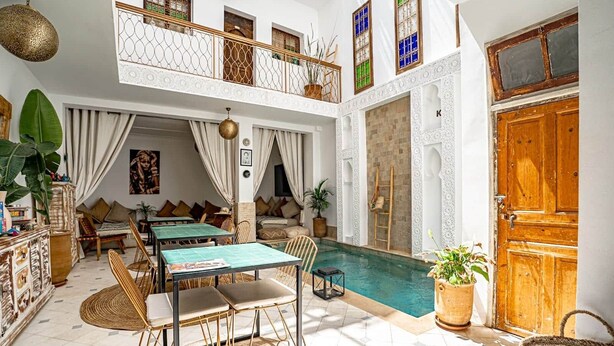 Amplia zona de piscina interior con comedor y balcón con barandillas decorativas.