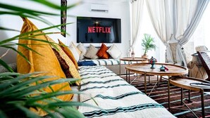 Una sala de estar con sofá, una mesa de centro y televisor montado en la pared.