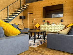 A modern living room with a staircase, a sofa set, a coffee table, and a cabinet with a decorative item. - Chalet panoramic view - 14 guests (Besse-et-Saint-Anastaise-Super Besse)