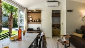 A modern interior with a dining area, a sofa, and a small table with a lamp. - Mobile home, AC, pets welcome - 6 guests (Saint-Cyprien)