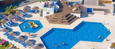 A large outdoor swimming pool with multiple lanes, sun loungers, and a children's play area.