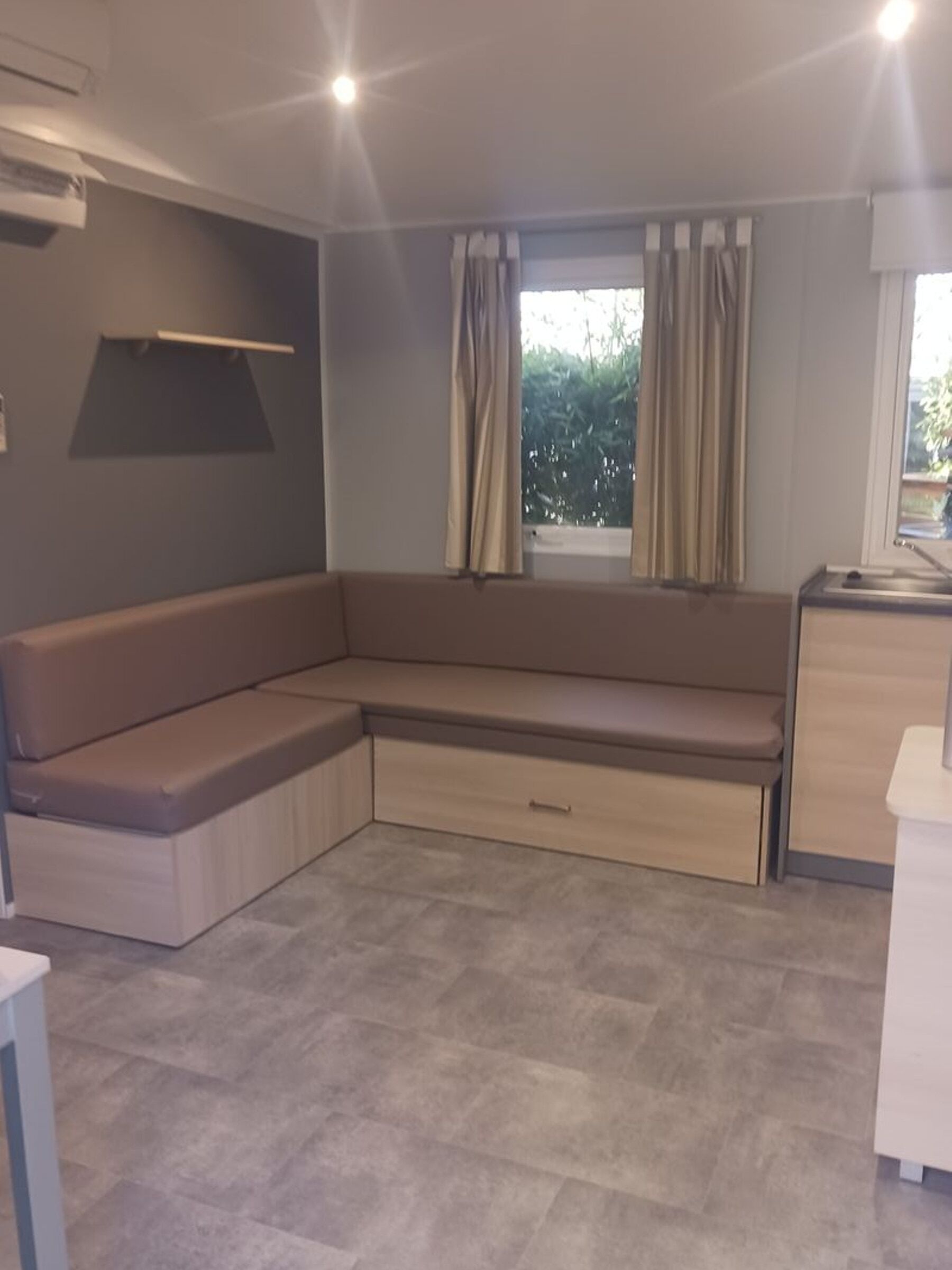 Une chambre moderne avec un banc intégré, un petit bureau et une fenêtre avec des rideaux.