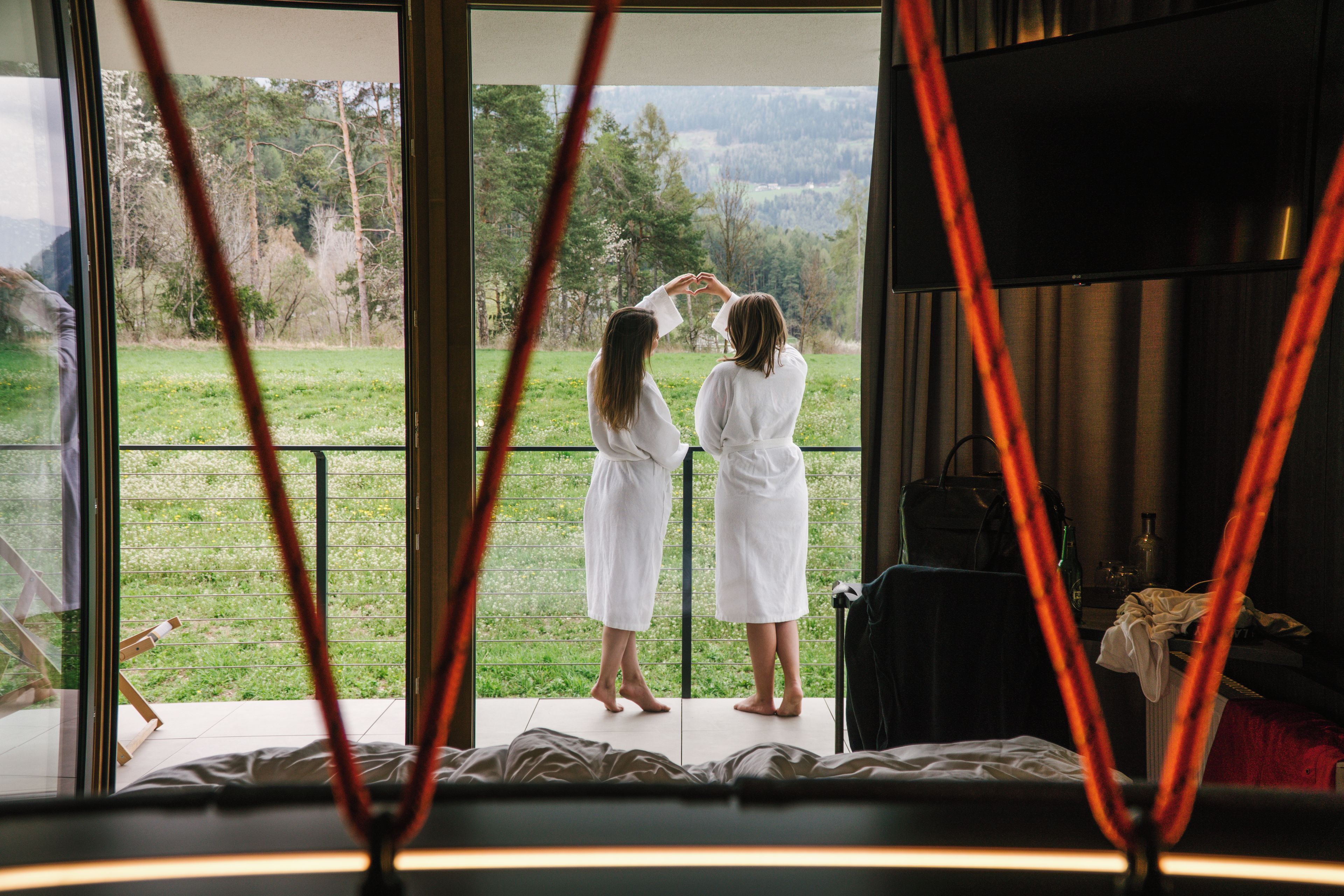 Ein Zimmer mit großem Fenster und Blick auf eine Wiese und Bäume.