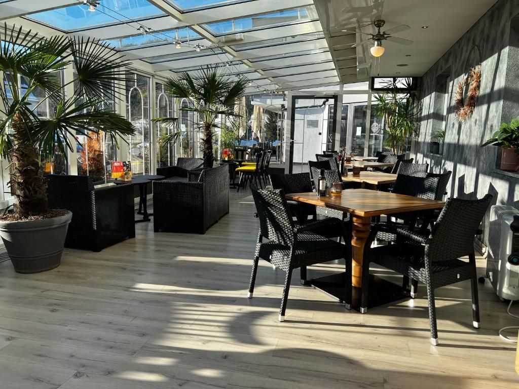 Un vaste espace intérieur doté d’un plafond en verre, d’un plancher en bois et de différents types de mobilier, notamment des tables et des chaises.
