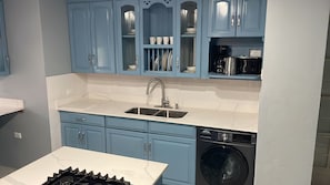 Una cocina con armarios azules, un lavamanos doble, un lavavajillas y una estufa.