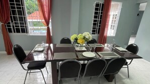 A dining area with a rectangular table set for six, surrounded by chairs, with windows and curtains. - 3-bedroom luxurious house in Kingston with pool, private parking free WiFi (Kingston)
