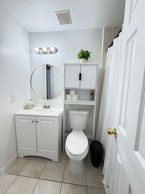 Un baño con lavamanos blanco, un inodoro, un espejo y un armario.