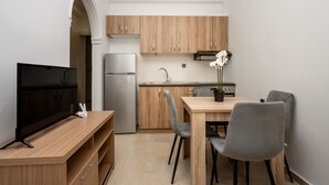 Una cocina compacta con armarios de madera, horno empotrado, lavamanos y comedor con mesa y sillas.