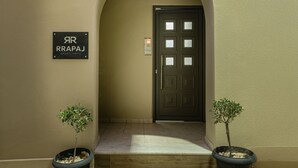 Una entrada arqueada con puerta, plantas en macetas y un cartel que indica 'RAPPAJ APARTMENTS'.