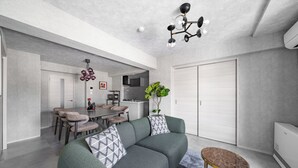 Ein modernes Wohnzimmer mit einer Eckcouch, einem Essbereich und einer Küche im Hintergrund.