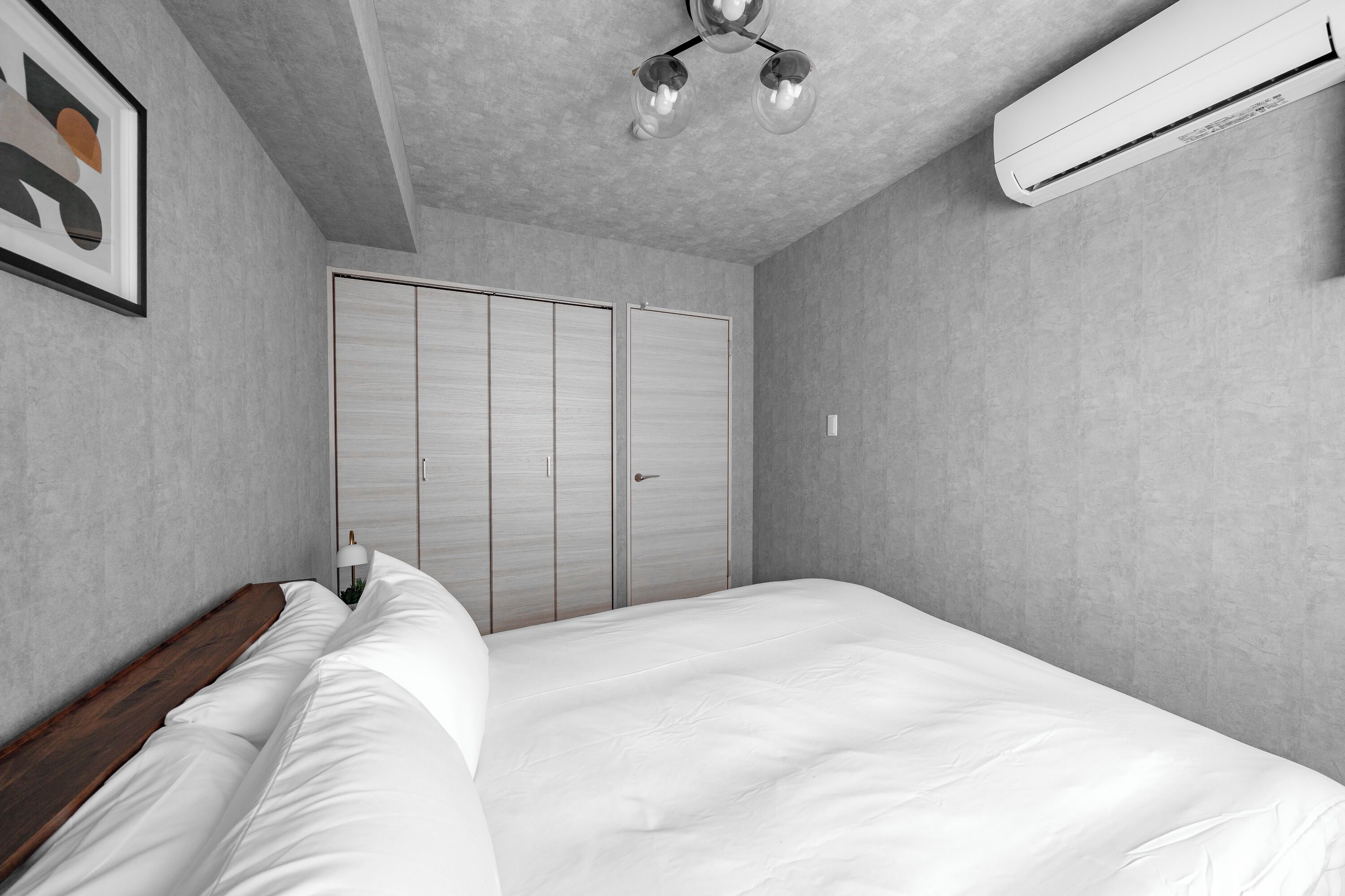 Ein Schlafzimmer mit Bett, Kleiderschrank, Deckenleuchte und Klimaanlage.