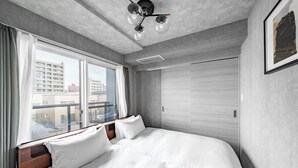 Ein Hotelzimmer mit einem großen Bett, einem Fenster mit Vorhängen, einer Deckenleuchte und einer Tür.
