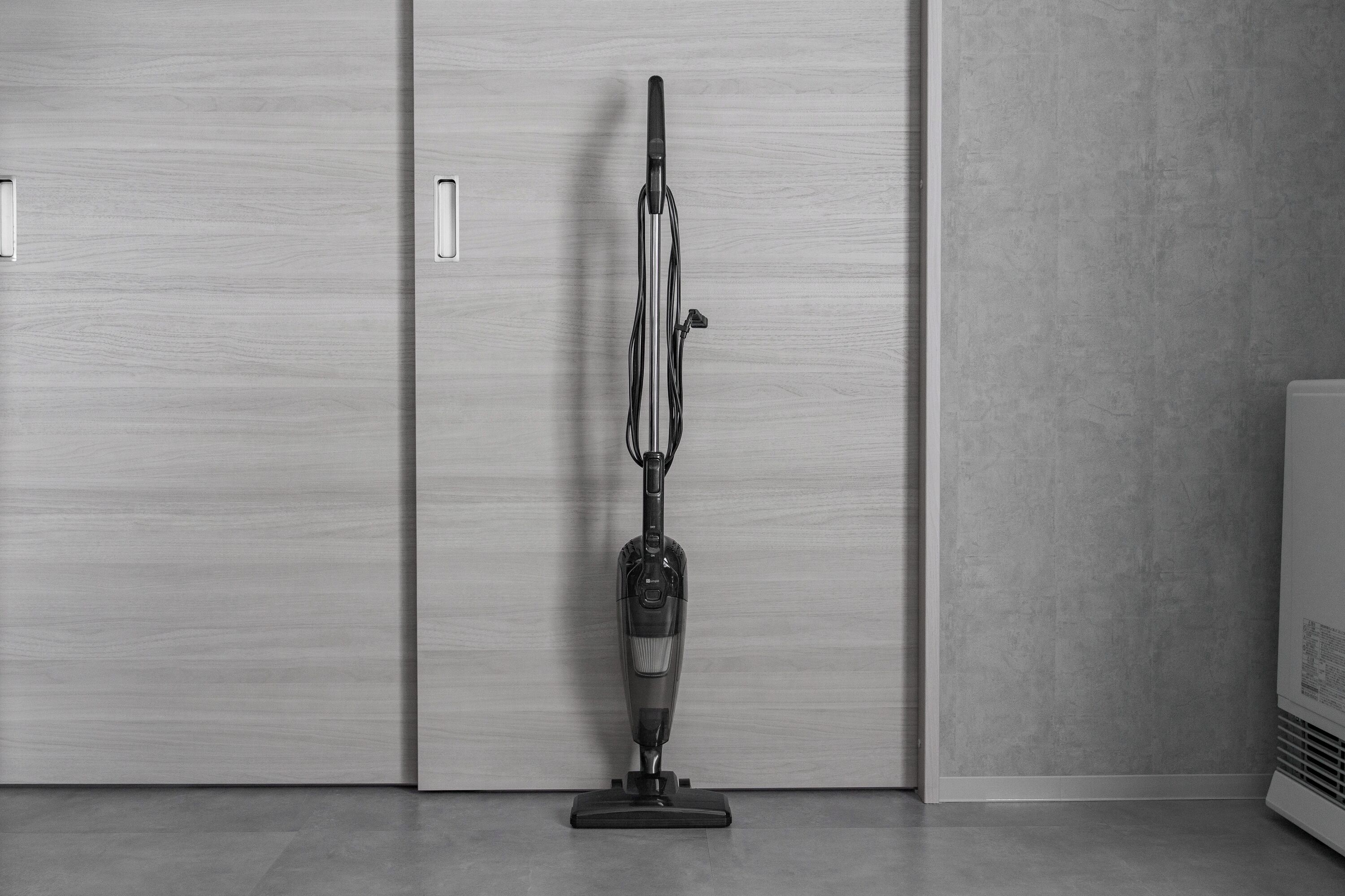 A vacuum cleaner in a room with a wooden floor and a large wardrobe with a handle.