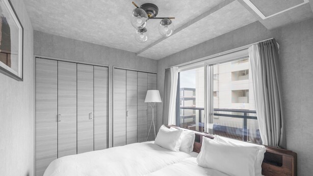 Ein Hotelzimmer mit einem großen Bett, einem Nachttisch, einer Lampe und Blick ins Freie.