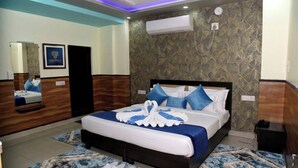 A hotel room with a bed, a mirror, a clock, and an air conditioning unit. - Hotel Tavooza Formely Sumangal (Gwalior)