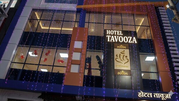 A building with a sign for 'HOTEL TAVOOZA' and a logo with a stylized animal. - Hotel Tavooza Formely Sumangal (Gwalior)