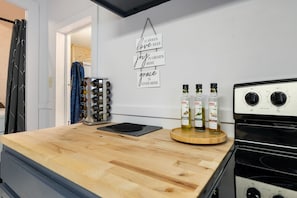 A kitchen with a wooden countertop, a black stove, and three bottles of olive oil on a wooden tray. - Cozy Anaconda Studio Near Main St & Hot Springs (Anaconda)