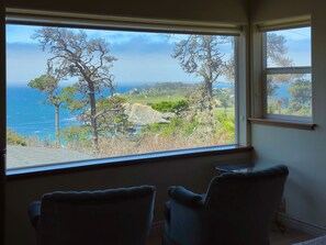 Ein Zimmer mit großem Fenster und Blick auf das Meer und die Küstenlandschaft.