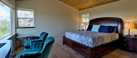 A bedroom with a wooden ceiling, a bed, a desk, and two chairs.